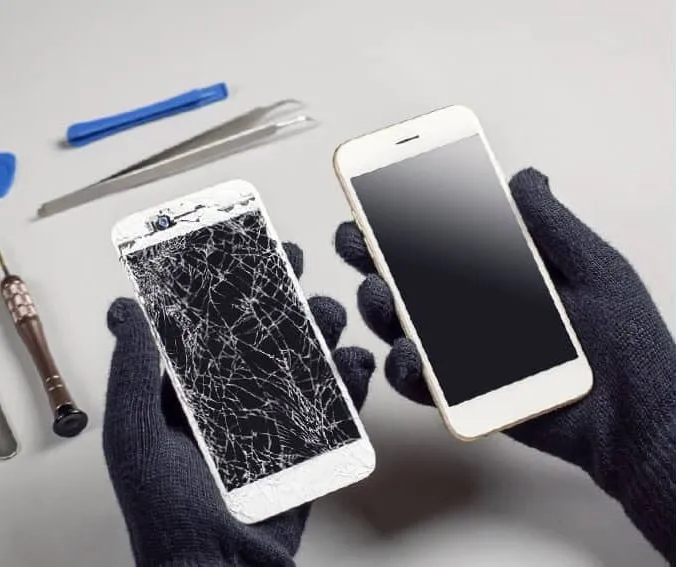 Smartphone mit gesprungenem Display neben einem reparierten Gerät und Werkzeug